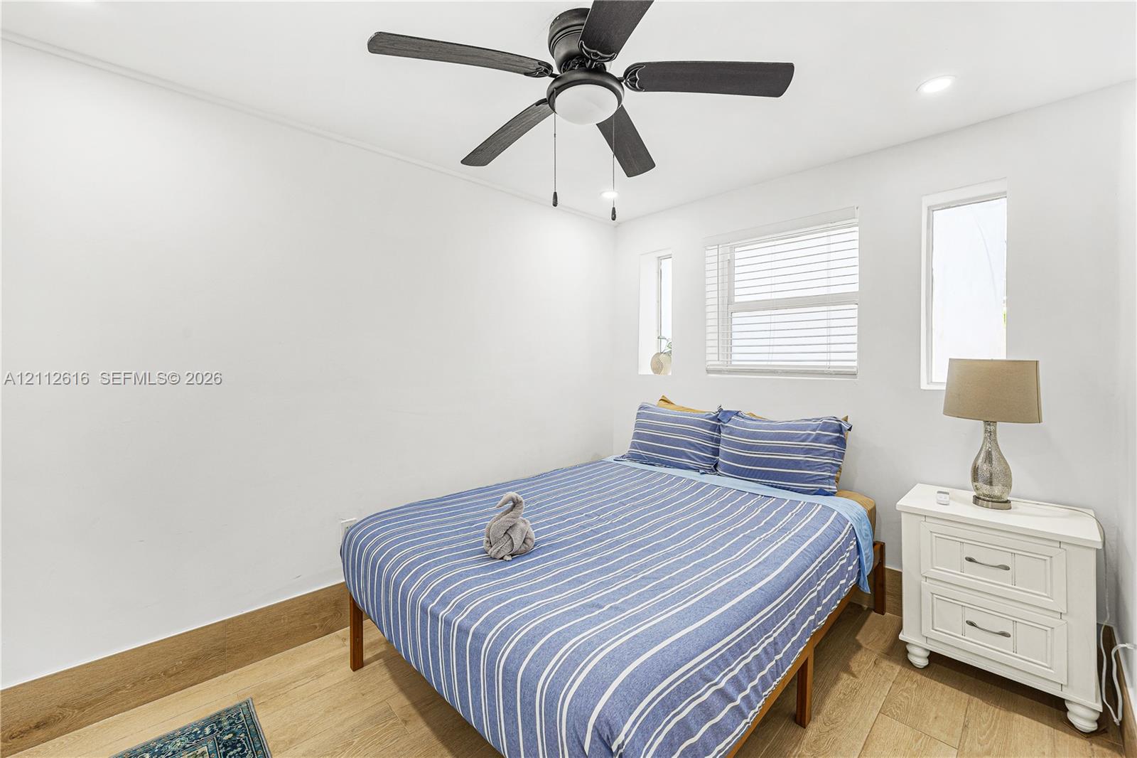 Neutral interior featuring wood-finish flooring, a multi-blade ceiling fan with integrated lighting, and recessed ceiling lights
