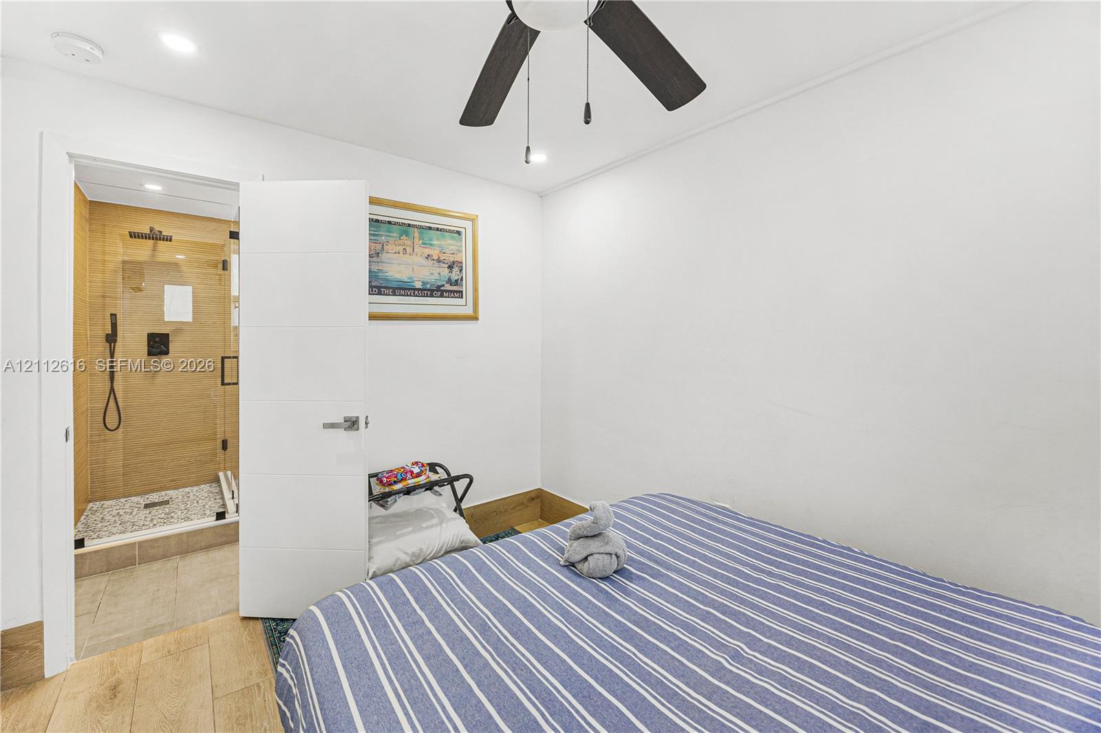 Bedroom featuring wood-finish flooring, ceiling fan, and recessed lighting, with a walk-in shower showcasing tiled walls and a glass enclosure