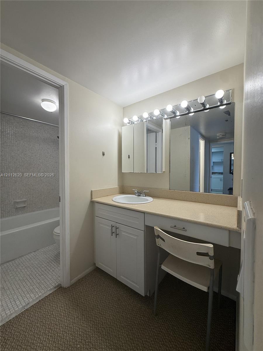 Vanity area featuring white cabinetry, an integrated surface-mount sink, an expansive countertop, a tri-fold medicine cabinet, and a multi-bulb light fixture