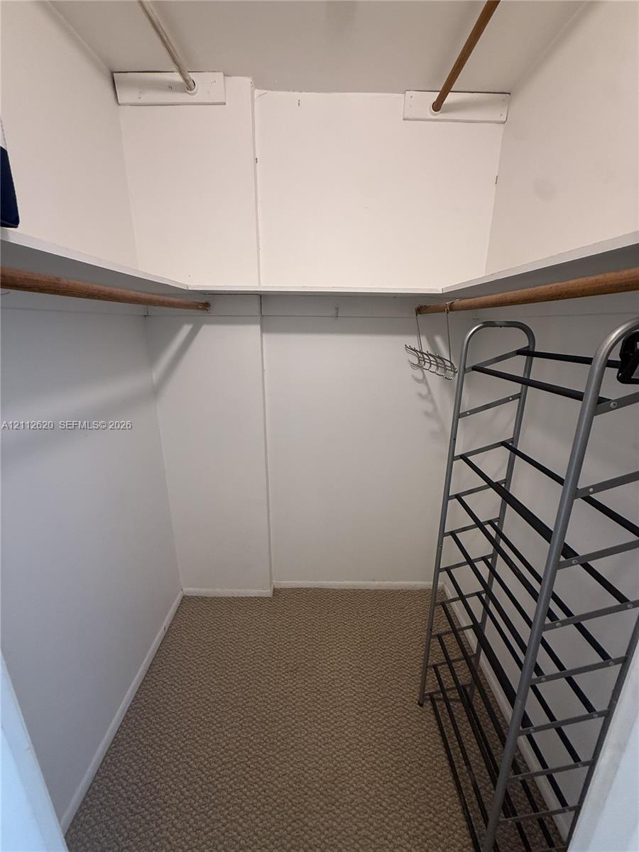 Reach-in closet featuring tiered shelving and integrated wooden clothing rods