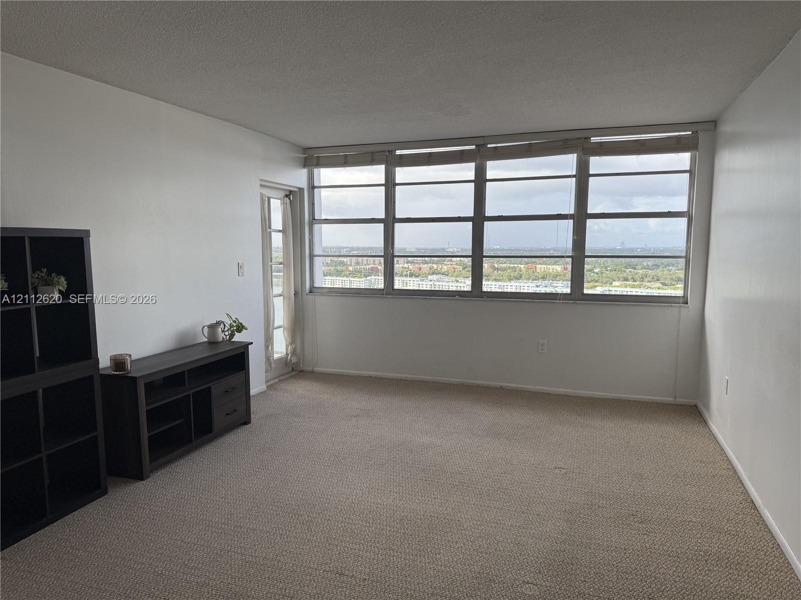 Expansive window wall with multiple panes, neutral carpeting, and a glass-panel exterior door