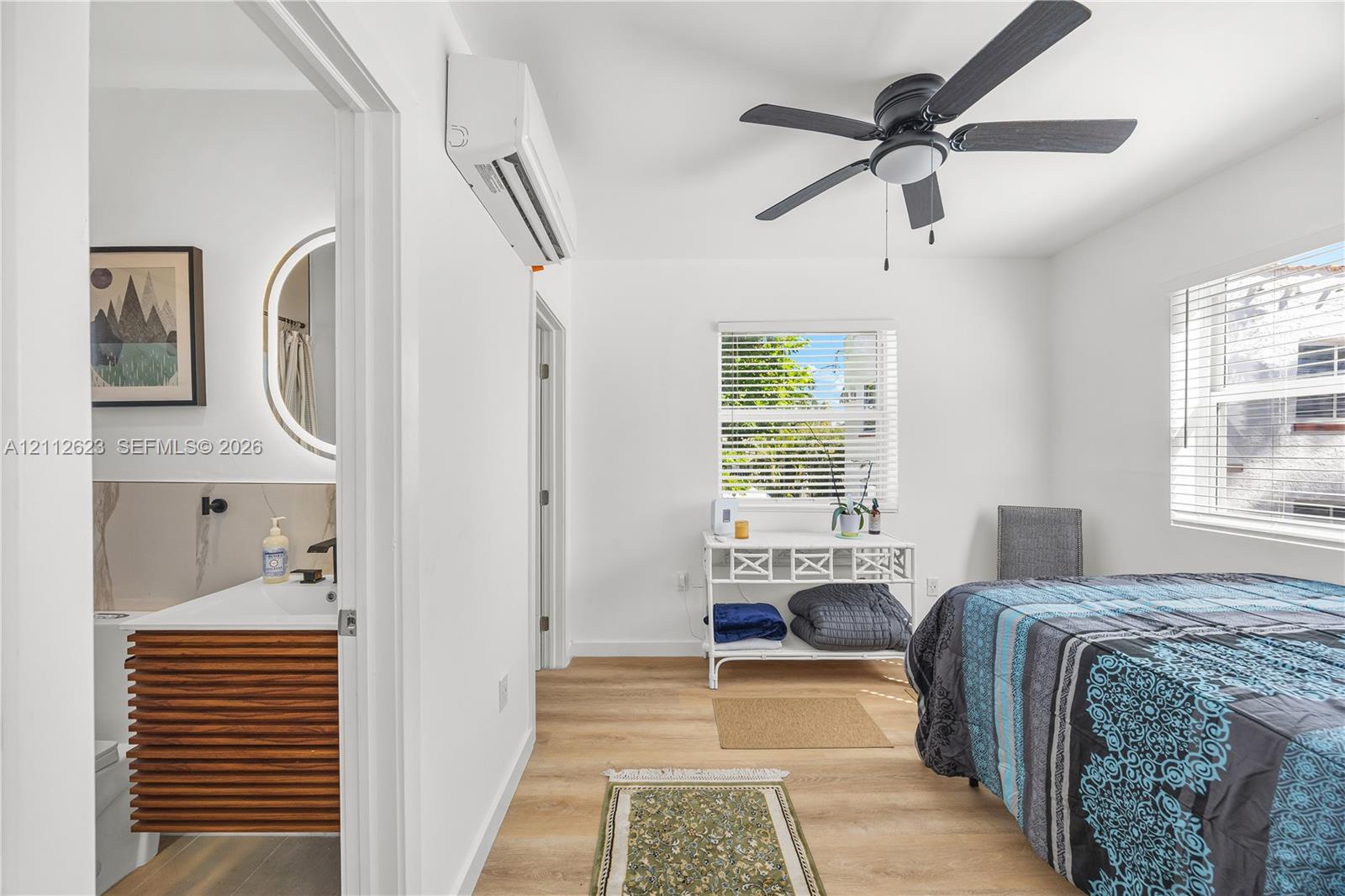 Interior space featuring wood-finish flooring, a wall-mounted ductless climate control unit, and a ceiling fan
