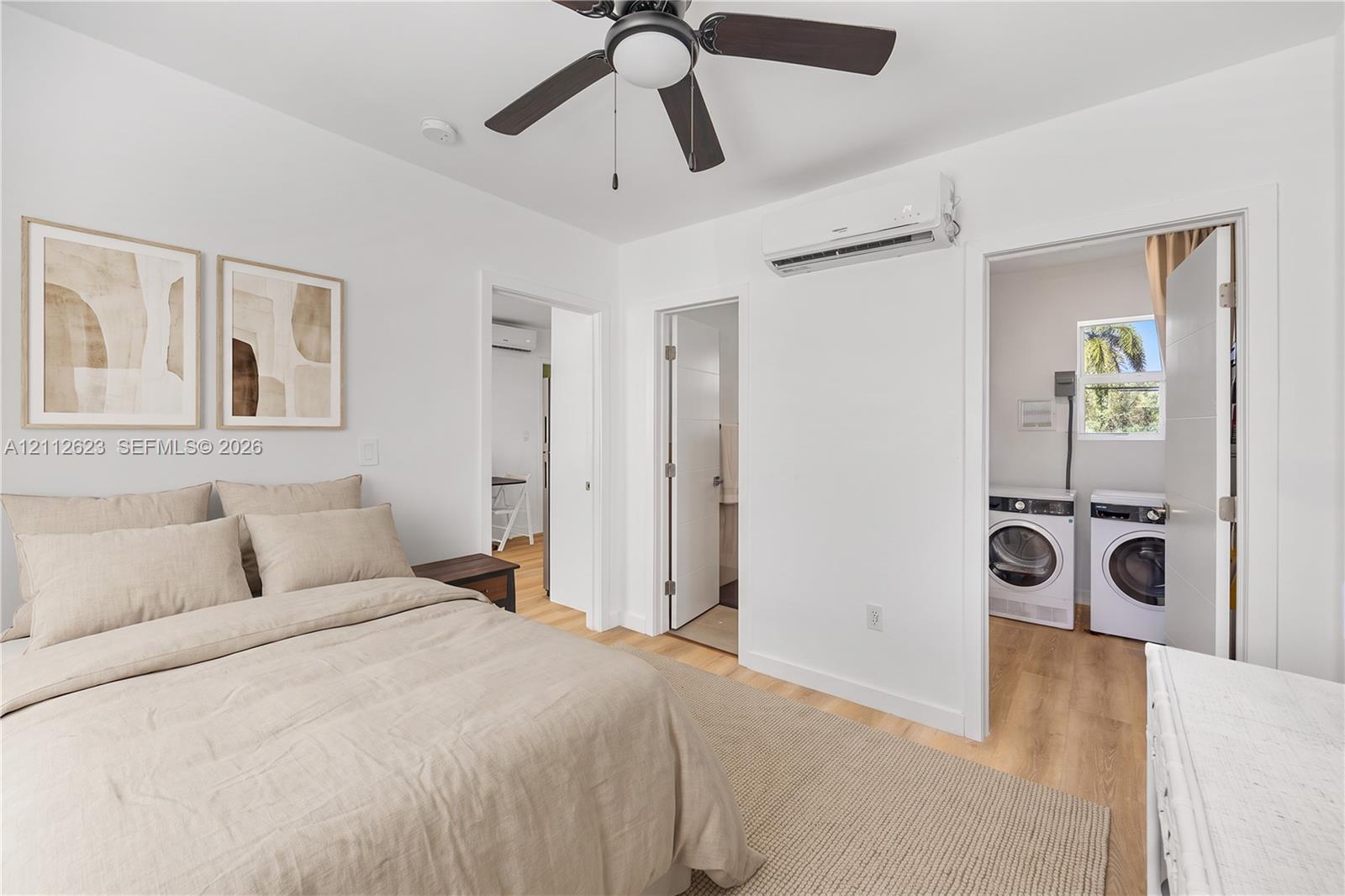 Room featuring wood-finish flooring, a ceiling fan with integrated lighting, and a wall-mounted ductless air conditioning unit