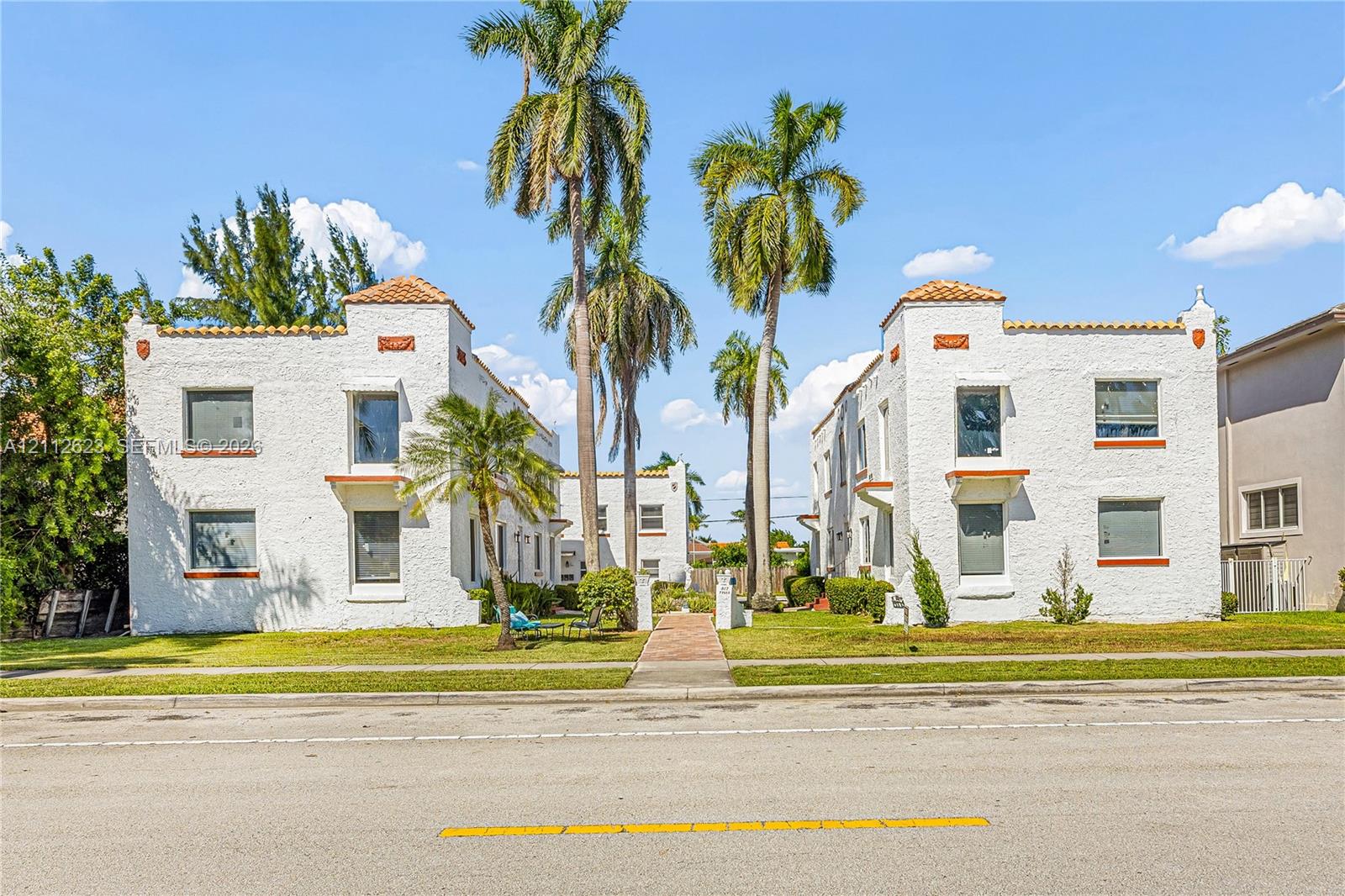 Spanish Revival multi-family architecture featuring white stucco exterior walls, terracotta tile roof accents, and symmetrical multi-level facades