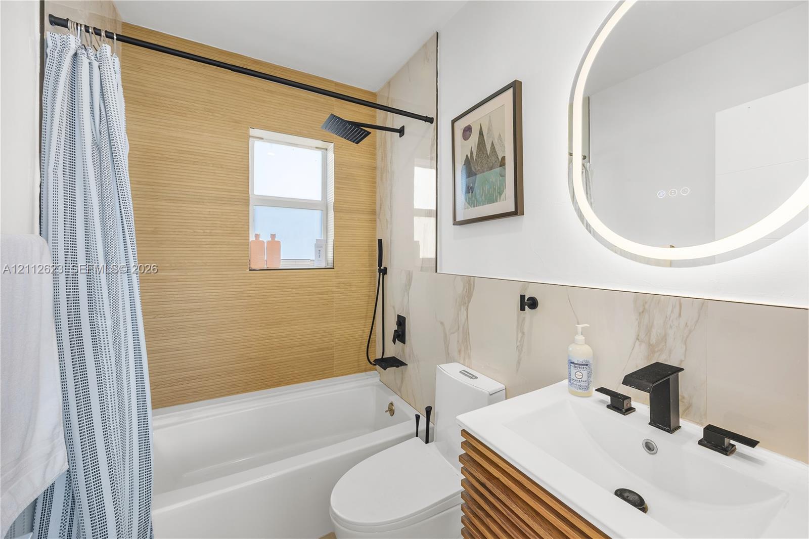 Bathroom featuring a vanity with wood-slat cabinetry, integrated sink, and matte black widespread faucet