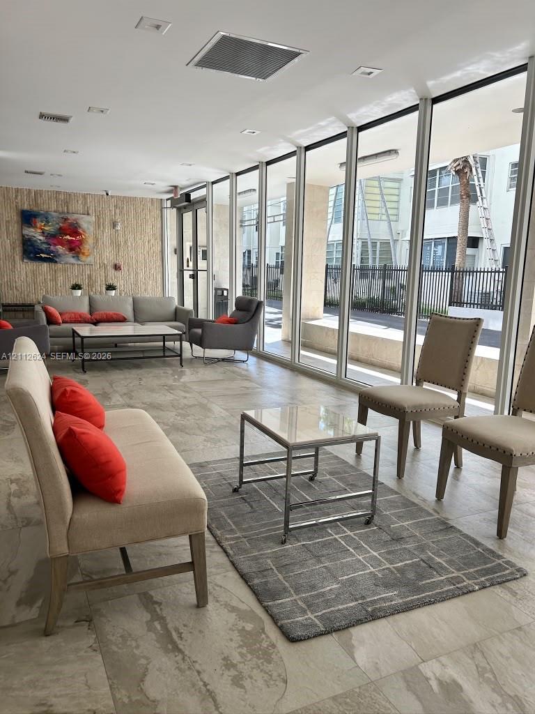 Floor-to-ceiling glass paneling, neutral tile flooring, and a stone-textured accent wall