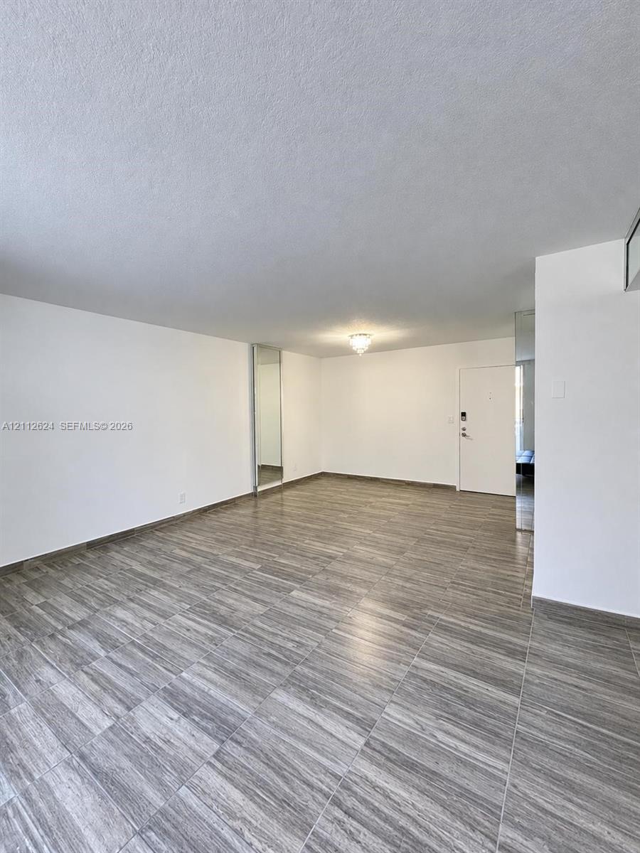 Open-concept room featuring neutral wall finishes, wood-finish tile flooring, recessed mirror panels, and a flush-mount ceiling light fixture
