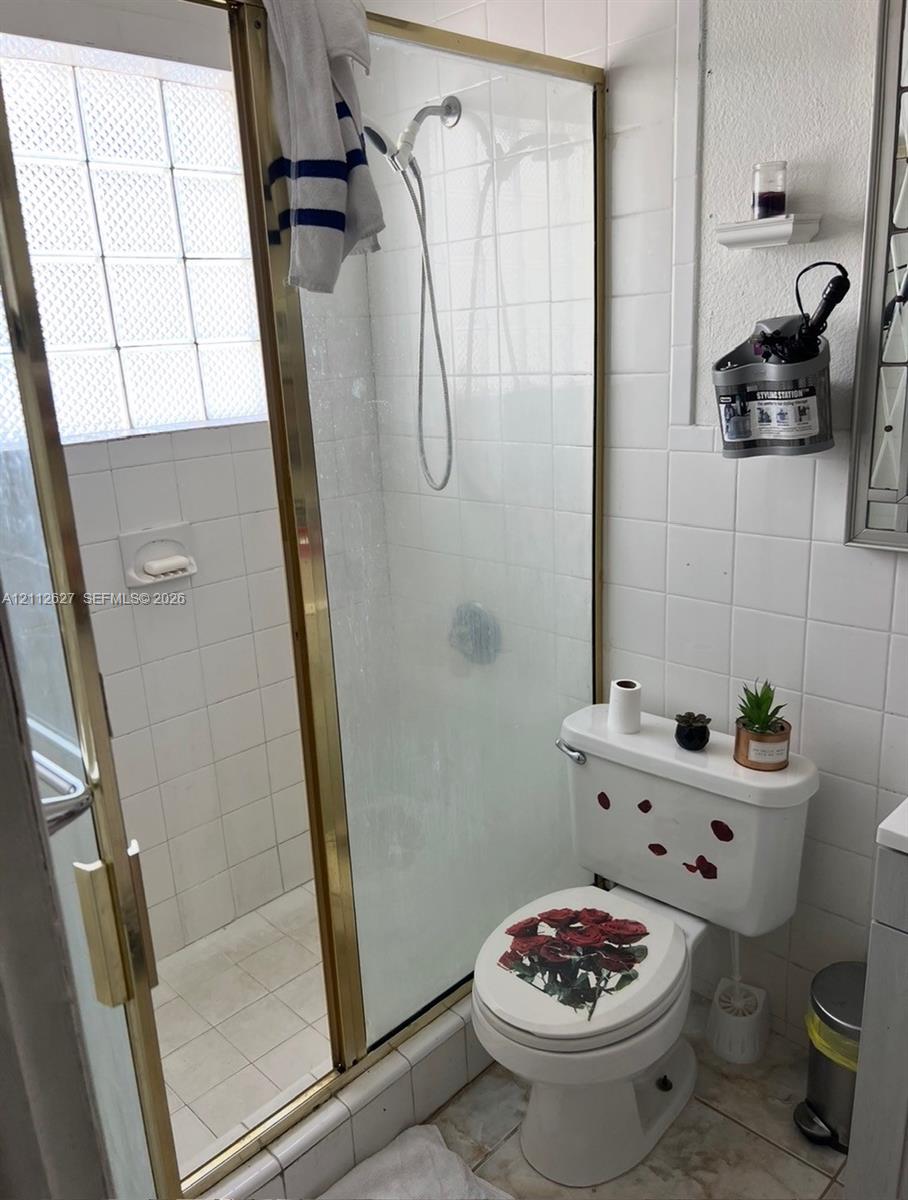 Walk-in shower enclosure featuring gold-tone metal framing and integrated glass block window