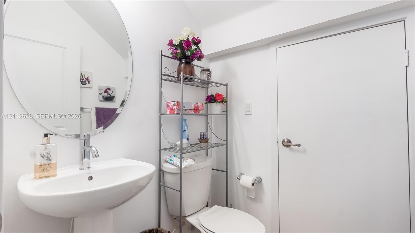 A stylish powder room centrally located among all common areas, featuring a perfect storage nook for cleaning supplies and a surplus of toiletrieskeeping everything organized and out of sight