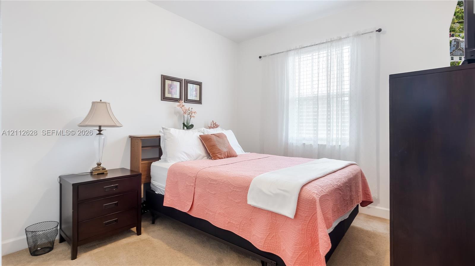 A serene secondary bedroom bathed in natural light, offering a comfortable retreat ideal for family, guests, or a stylish home office setup.