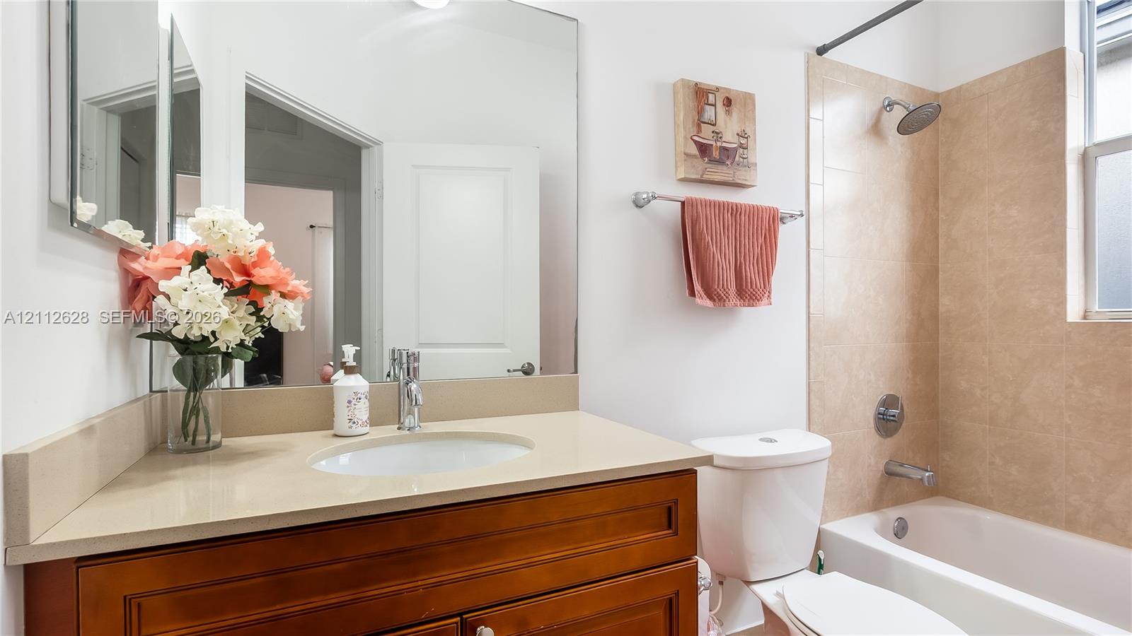 A beautifully maintained secondary bathroom featuring a spacious vanity, warm finishes, and a bright shower-tub combinationperfect for guests, family, or multigenerational living.