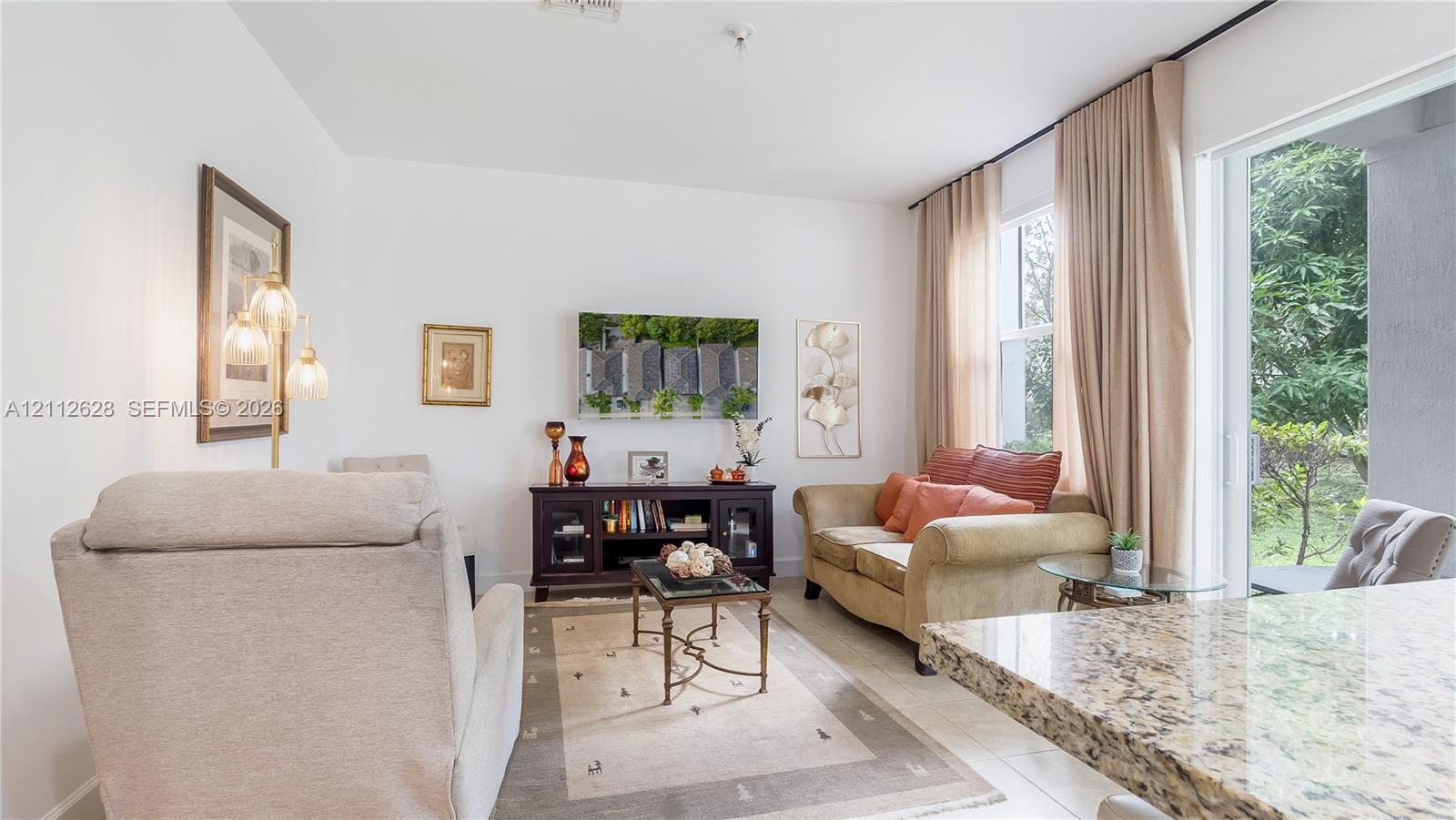 This light-filled living room off the kitchen offers a sophisticated yet cozy space for daily relaxation, casual gatherings, and effortless comfort- all furniture is included.