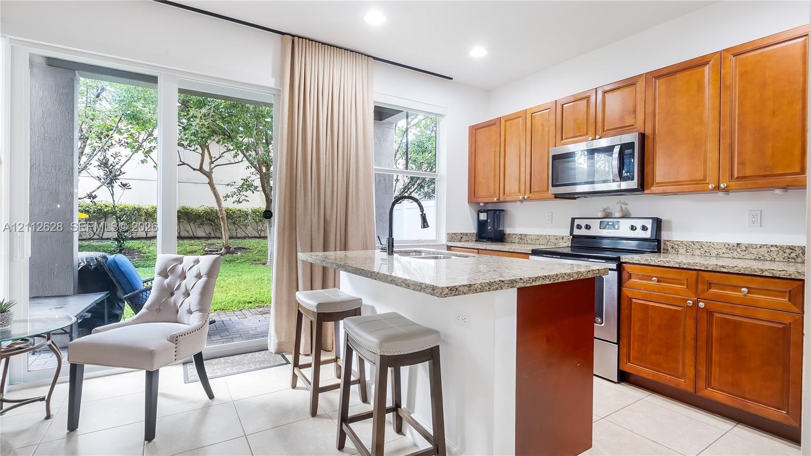 Bathed in natural light, this chef-inspired kitchen showcases premium stainless steel appliances and a polished granite islandcomplete with elegant seating for effortless, casual dining.
