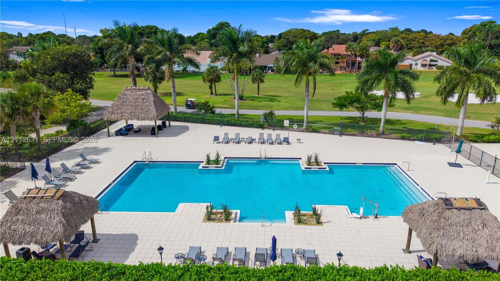 Swimming pool featuring a tiled deck, built-in structural planters, and multiple thatched-roof pavilions