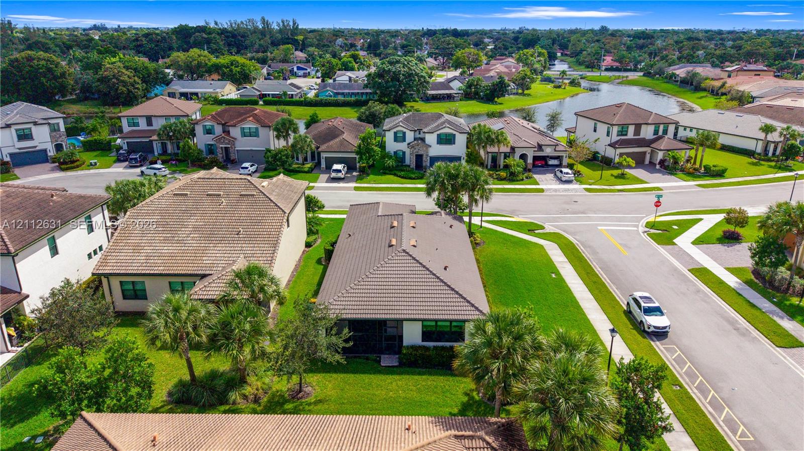 Aerial perspective of a single-story residence featuring a hipped tile roof, concrete driveway, attached multi-car garage, and manicured landscaping