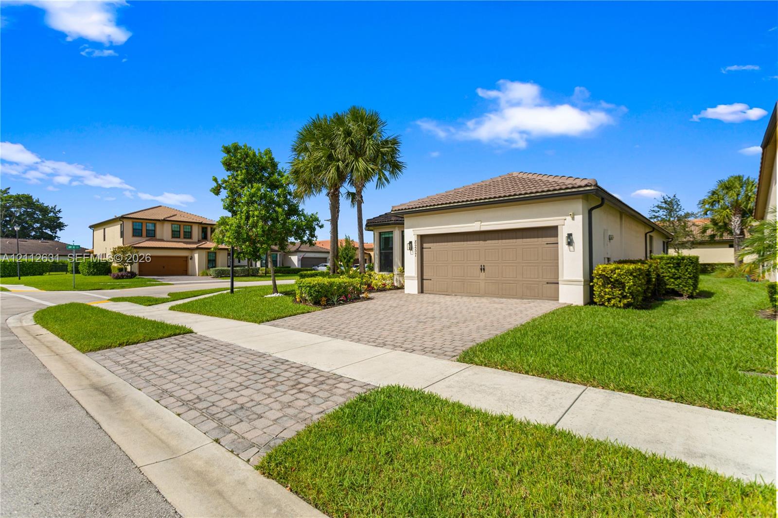 Stucco exterior featuring a paver driveway, multi-car garage, and mature landscaping Stucco exterior featuring a paver driveway, multi-car garage, and mature landscaping