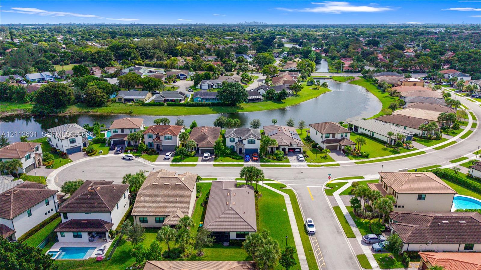 Aerial perspective of a residential community featuring winding paved streets, manicured landscaping, and a central water feature