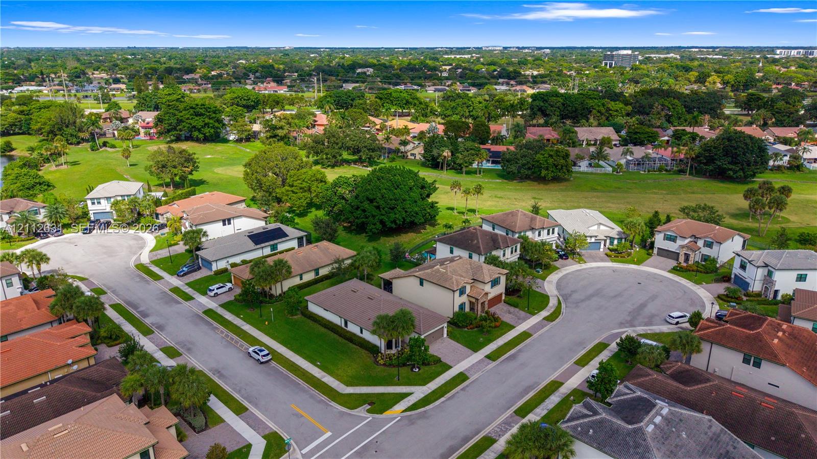 Aerial perspective of a residential neighborhood featuring cul-de-sac streets, surrounding greenery, and proximity to an expansive open-space fairway