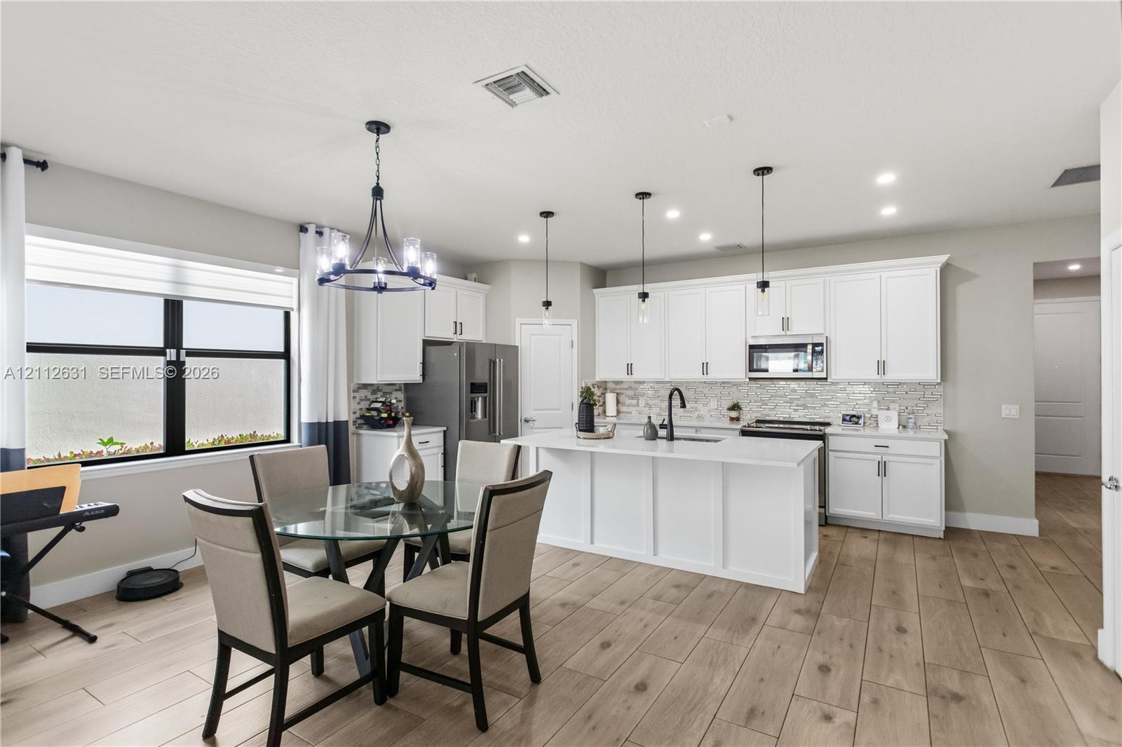 Kitchen featuring white cabinetry, a center island with a stone-finish countertop, wood-finish flooring, a decorative chandelier, and recessed lighting