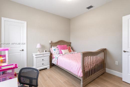 Neutral-toned interior space featuring wood-finish flooring, two white paneled doors, and a ceiling-mounted light fixture
