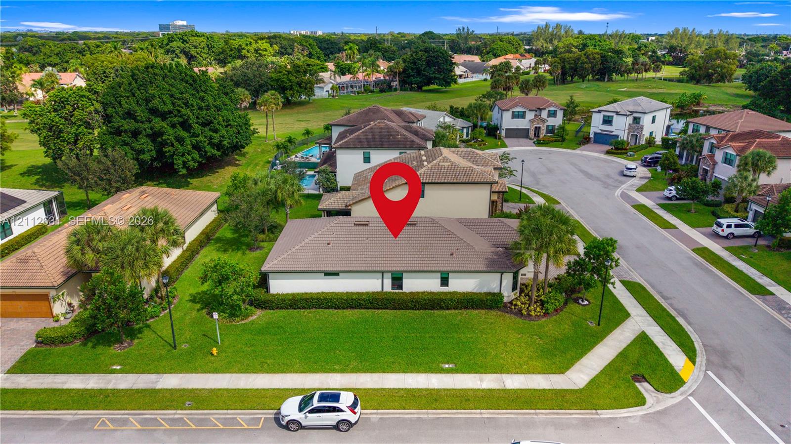 Single-story residence featuring a tile roof, light-toned exterior finish, corner lot placement, mature landscaping, and an attached multi-car garage