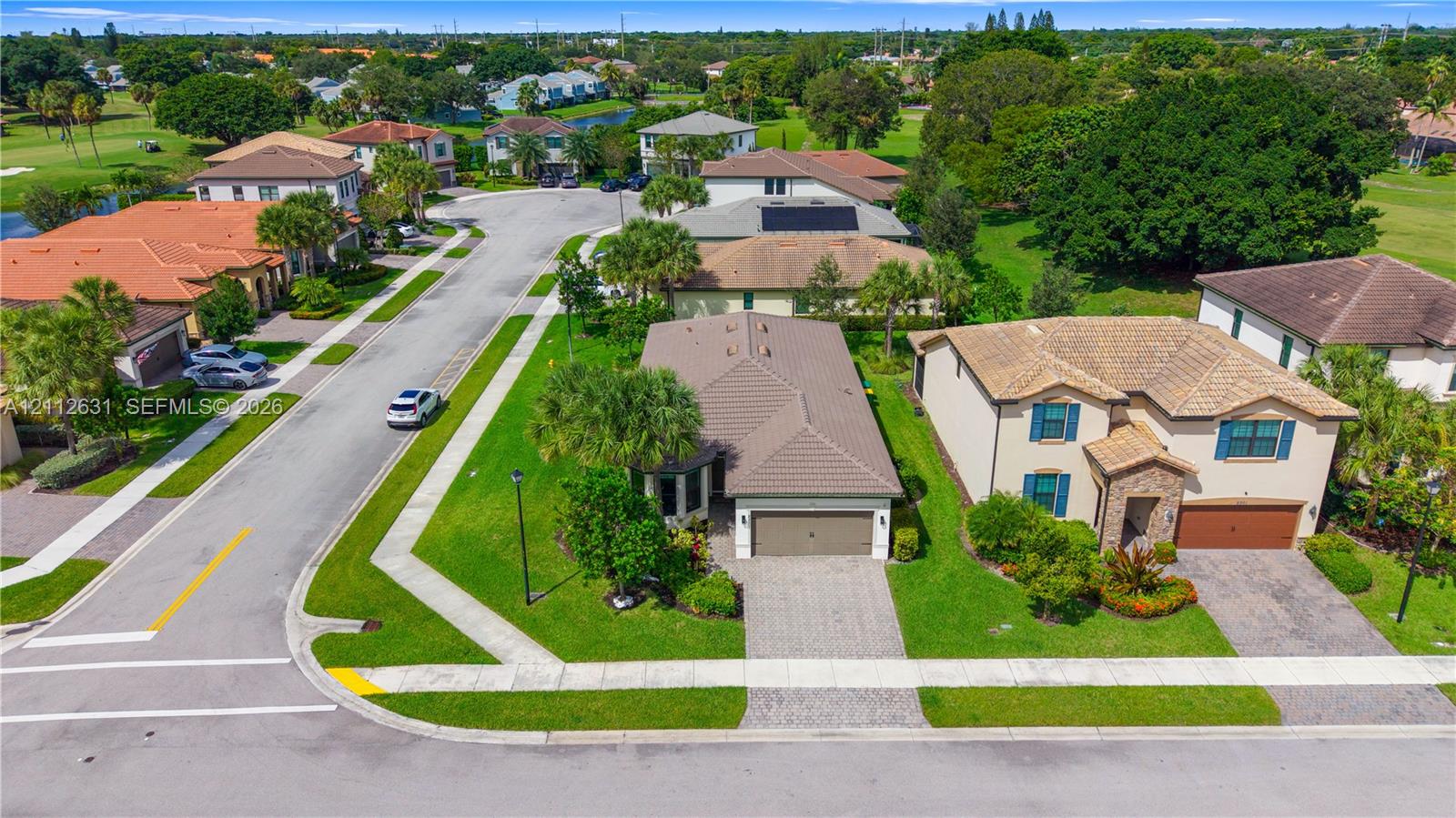 Aerial perspective featuring concrete tile roof systems, paver driveways, manicured green space, and mature landscape plantings
