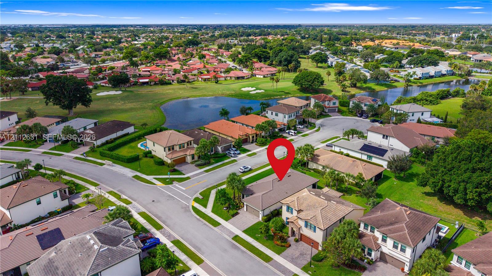 Aerial perspective of a multi-story residence featuring a tile roof, paved driveway, multi-car garage, and landscaped front yard