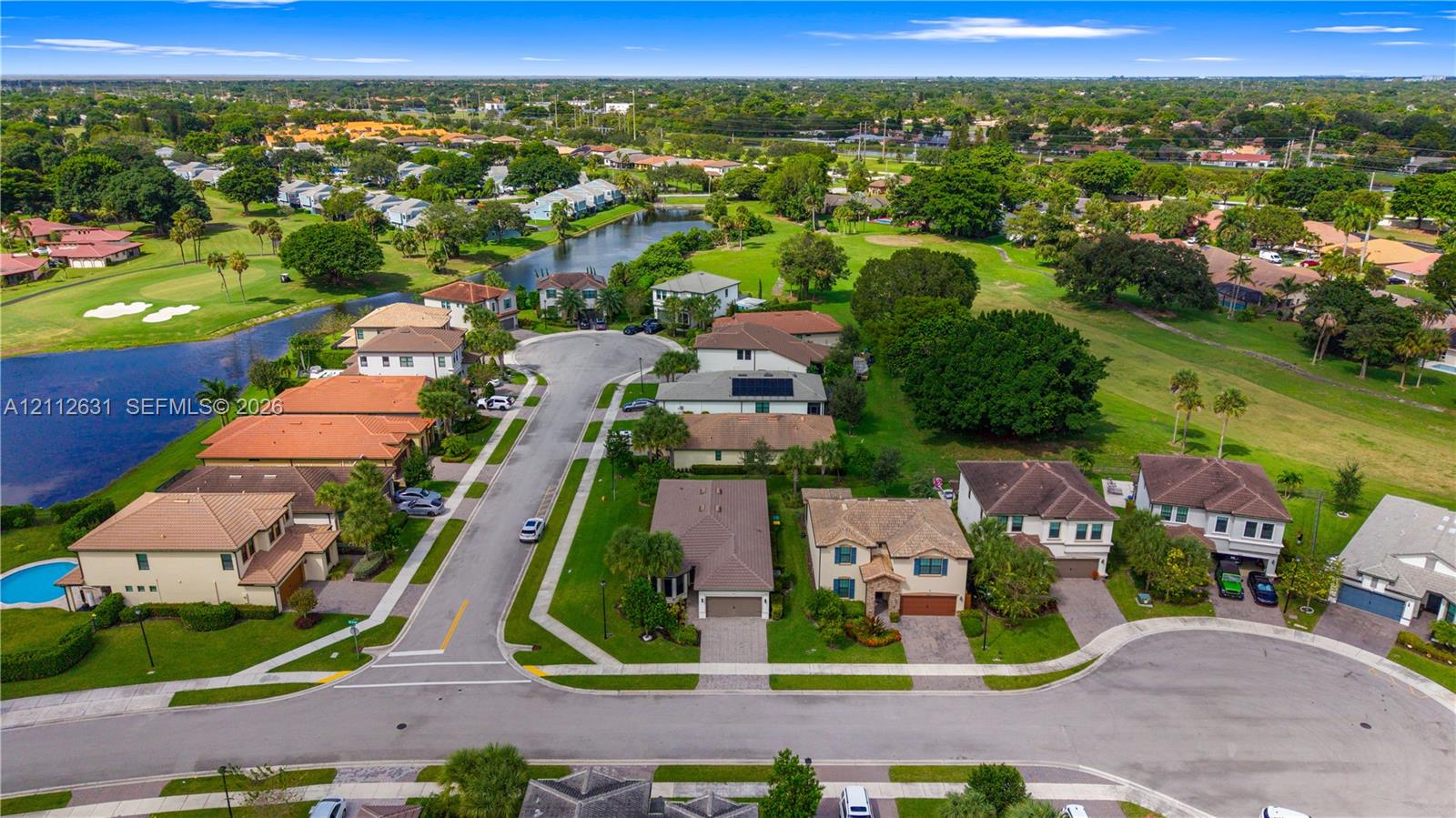 Aerial perspective of a residential community featuring paved cul-de-sac streets, established landscaping, integrated water features, and expansive greenery