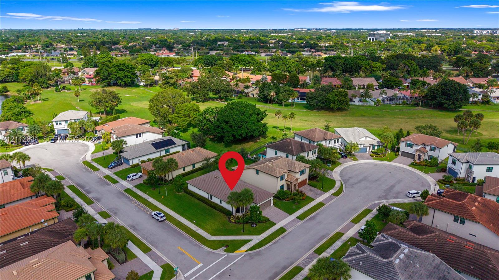 Aerial perspective of a single-story residence situated on a corner lot featuring a multi-hip roof, integrated garage, and expansive lawn area