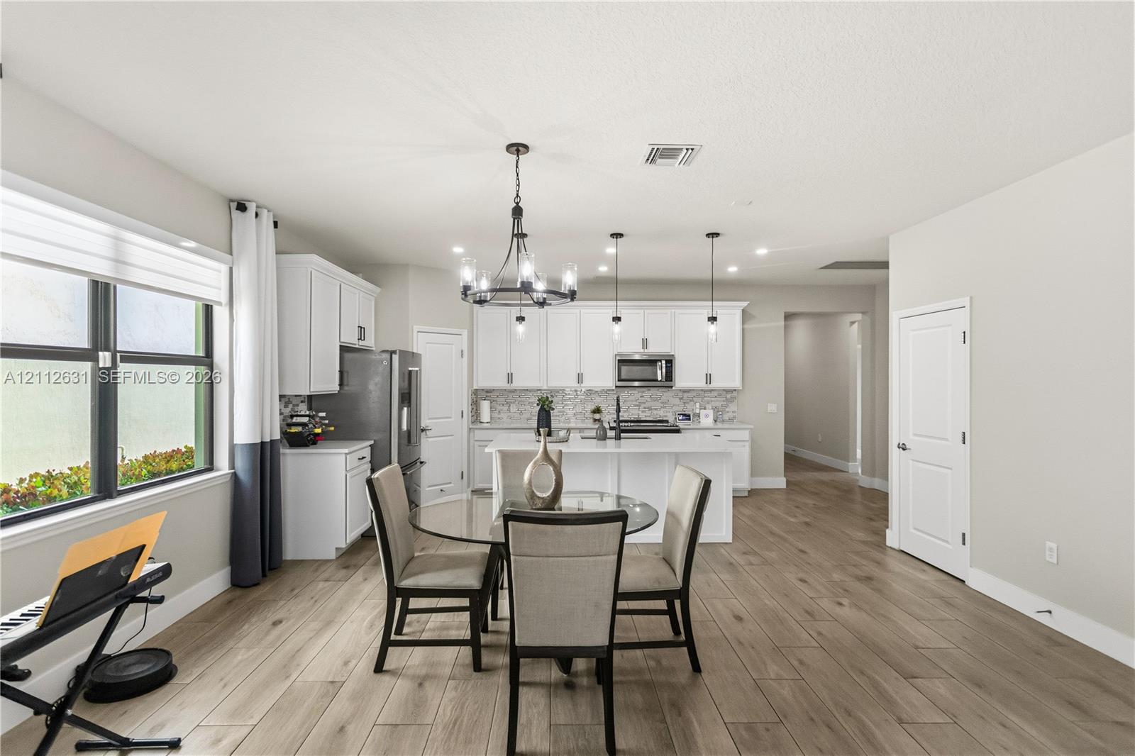 Kitchen featuring white cabinetry, center island with quartz countertops, wood-finish flooring, and decorative chandelier lighting