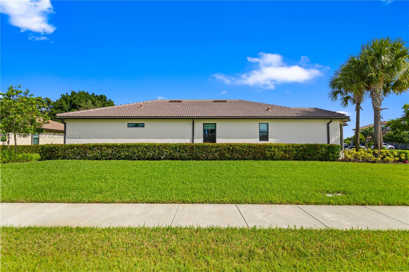 Exterior elevation featuring a tile roof, stucco siding, and a manicured hedge border Exterior elevation featuring a tile roof, stucco siding, and a manicured hedge border