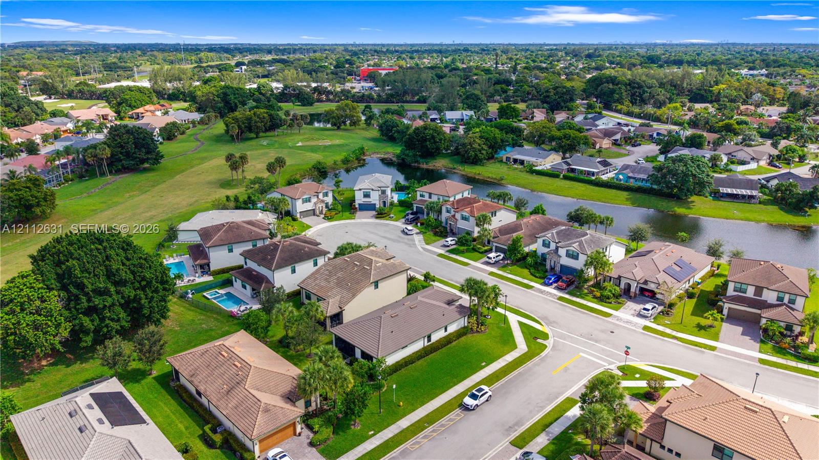 Aerial perspective of a residential neighborhood featuring homes with tile roofing, mature landscaping, manicured lawns, and waterfront access