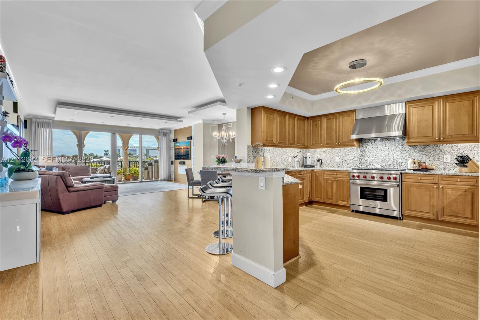 Open-concept kitchen featuring shaker-style wood cabinetry, stainless steel professional-grade range, stone-tiled backsplash, and wood-finish flooring throughout