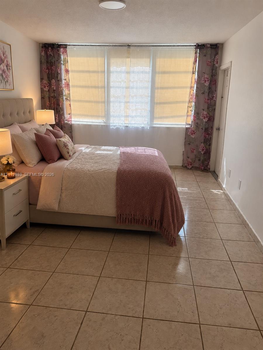 Spacious room featuring oversized windows with natural light, neutral ceramic tile flooring, and flush-mount ceiling lighting