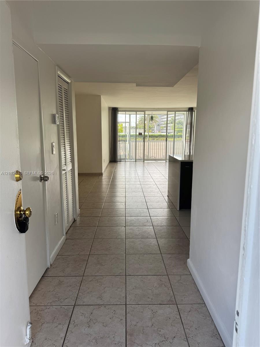 Ceramic tile flooring, louvered bi-fold closet doors, and floor-to-ceiling glass sliding doors opening to a balcony