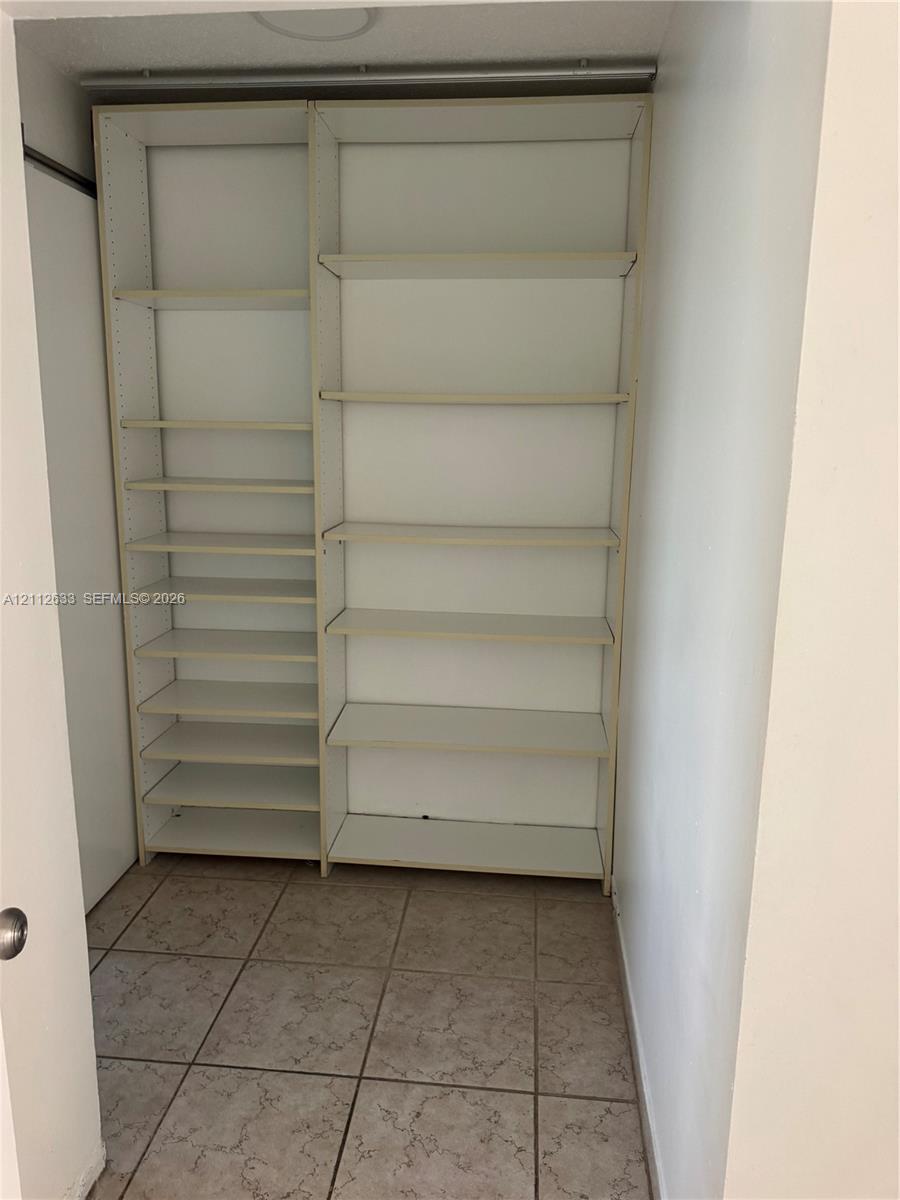 Built-in white storage shelving featuring adjustable shelving units and tiled flooring