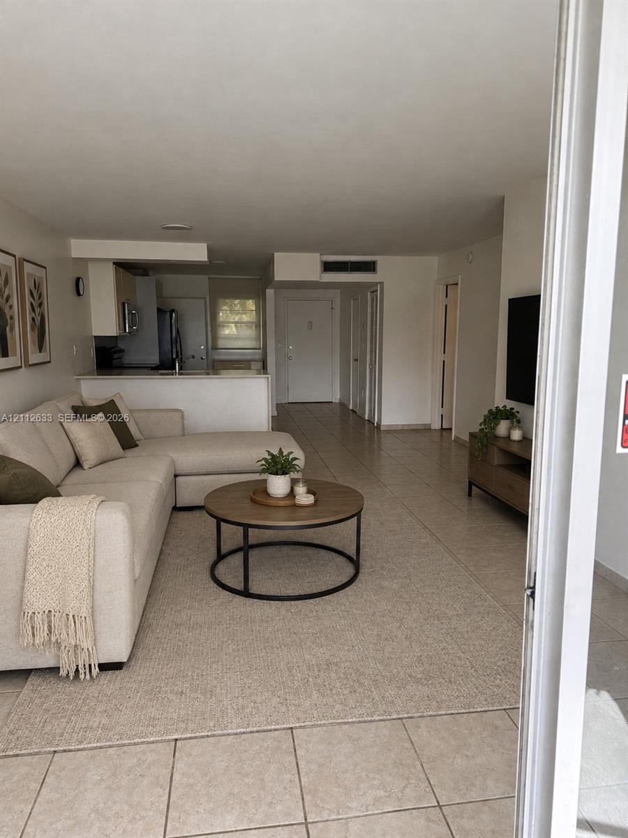Open-concept floor plan featuring tile flooring, neutral wall tones, and a kitchen breakfast bar