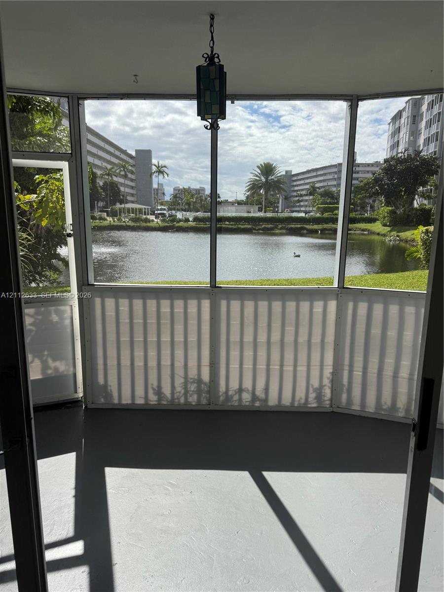 Screened-in enclosure featuring a hanging lantern-style light fixture, concrete flooring, and water frontage
