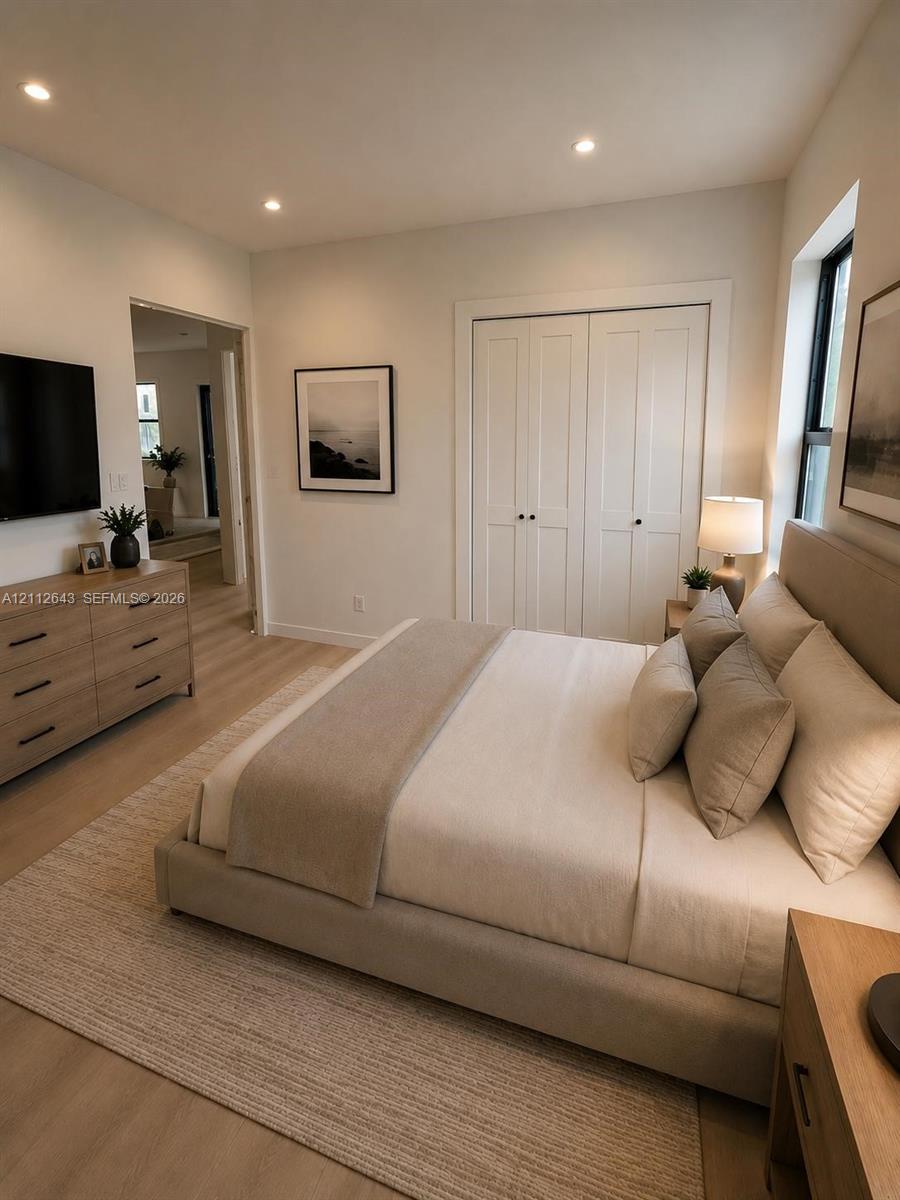 Neutral-toned interior featuring wood-finish flooring, recessed lighting, and double-panel closet doors Neutral-toned interior featuring wood-finish flooring, recessed lighting, and double-panel closet doors