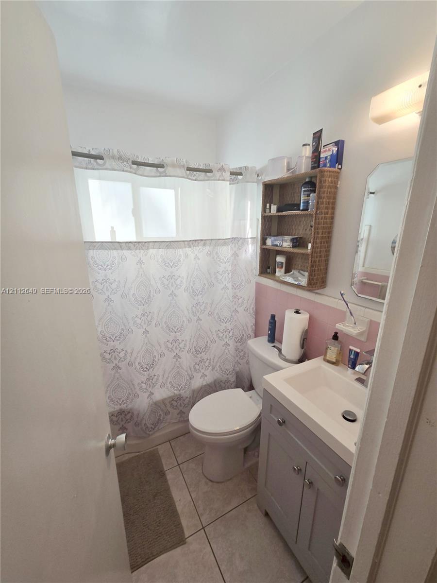 Bathroom featuring a gray vanity with an integrated rectangular sink, tile flooring, and a tub-shower combination with a surround