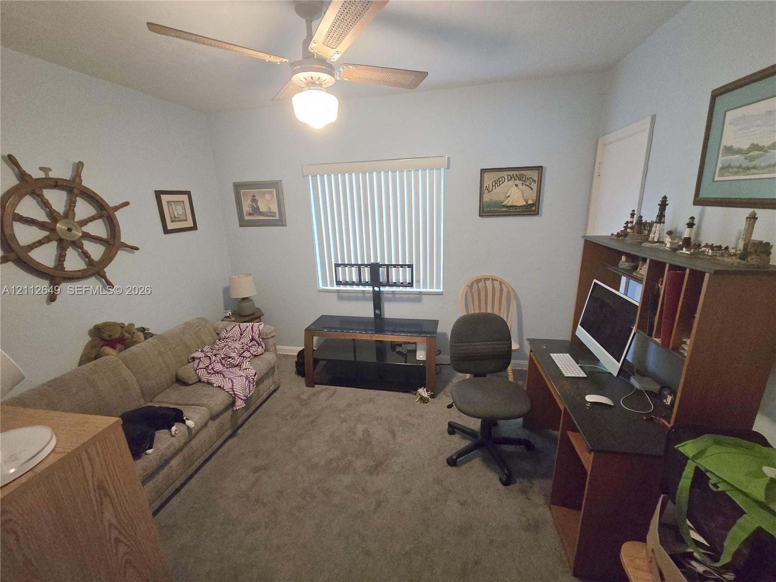 Carpeted room featuring a ceiling fan with integrated light fixture and vertical slat window blinds Carpeted room featuring a ceiling fan with integrated light fixture and vertical slat window blinds