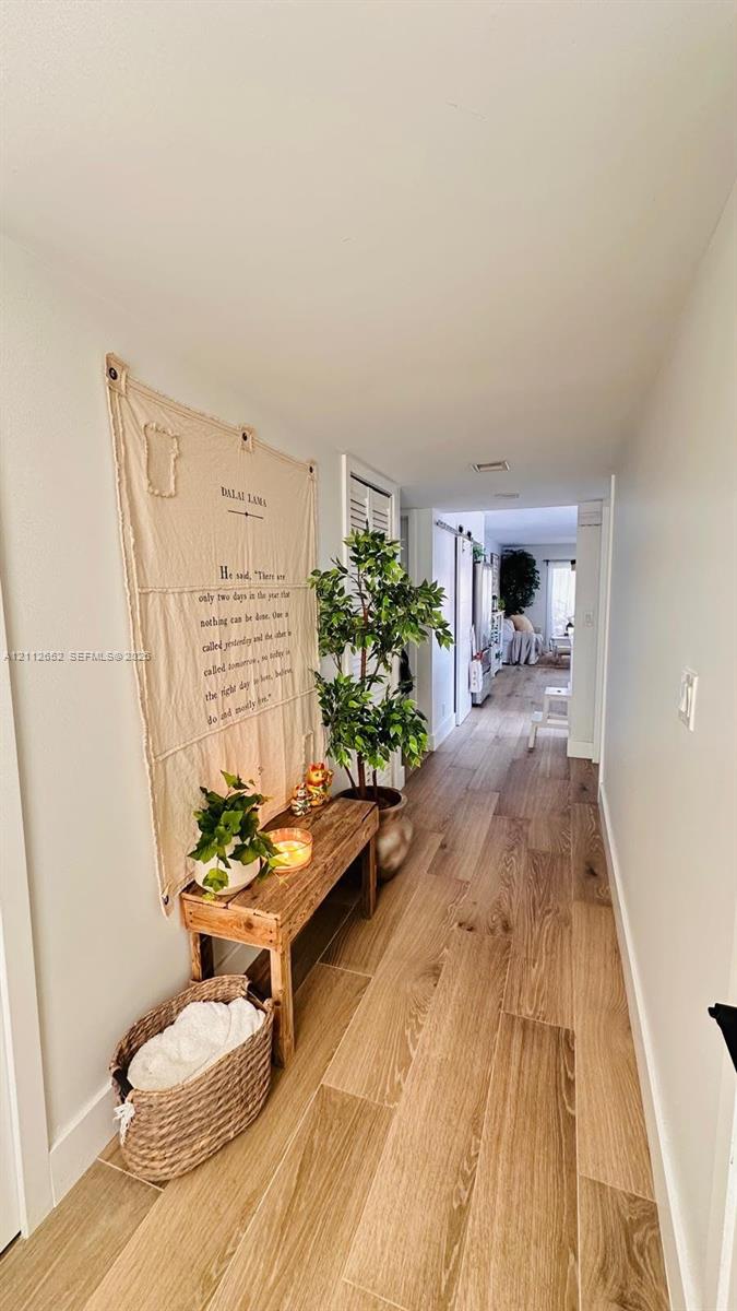 Hallway featuring wood-finish flooring and louvered closet doors