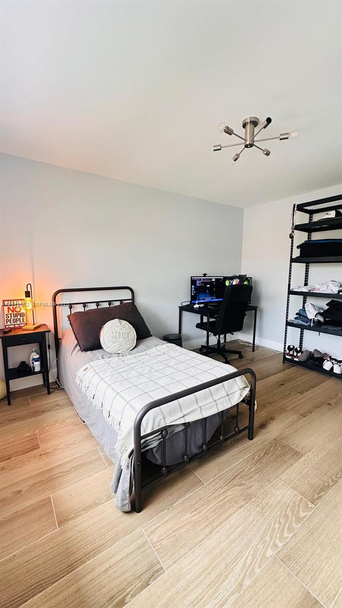 Room featuring neutral wall paint, wood-finish flooring, and a modern multi-arm light fixture