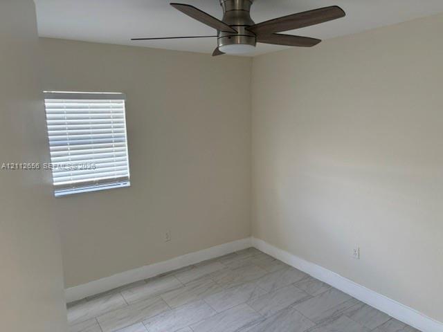 Neutral-toned walls featuring stone-finish floor tile, a ceiling fan with integrated lighting, and a window equipped with horizontal blinds