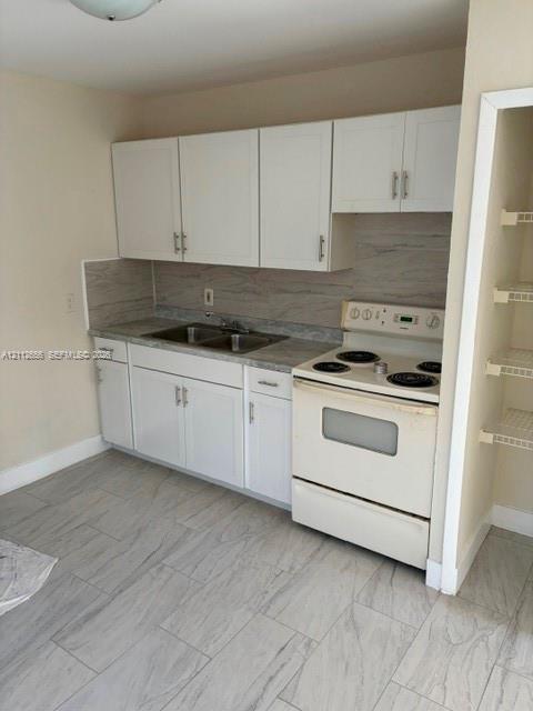 Kitchen featuring white shaker-style cabinetry, stone-pattern laminate countertops, stainless steel dual-basin sink, electric range, and ceramic tile flooring