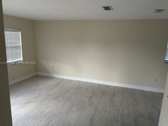 Neutral interior space featuring wood-finish flooring, light-toned walls, and windows with horizontal blinds