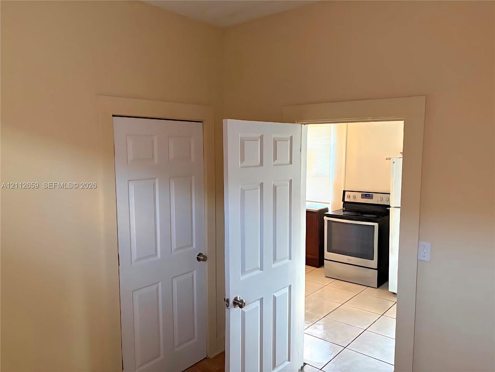 Interior features include six-panel wooden doors, neutral wall paint, tile flooring, and a stainless steel freestanding range