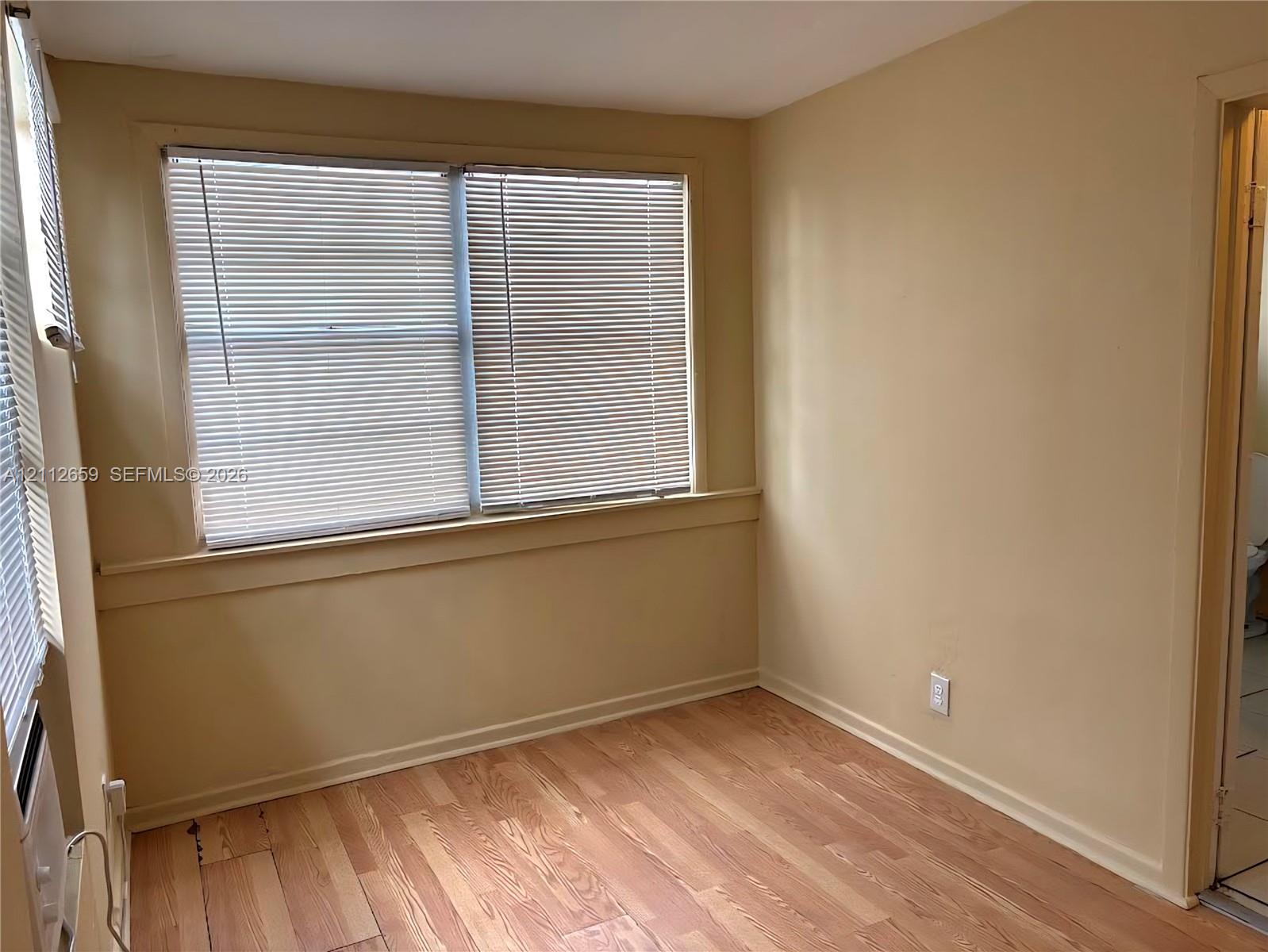 Wood-finish flooring, neutral wall tones, and horizontal window blinds featuring a window sill and chair rail
