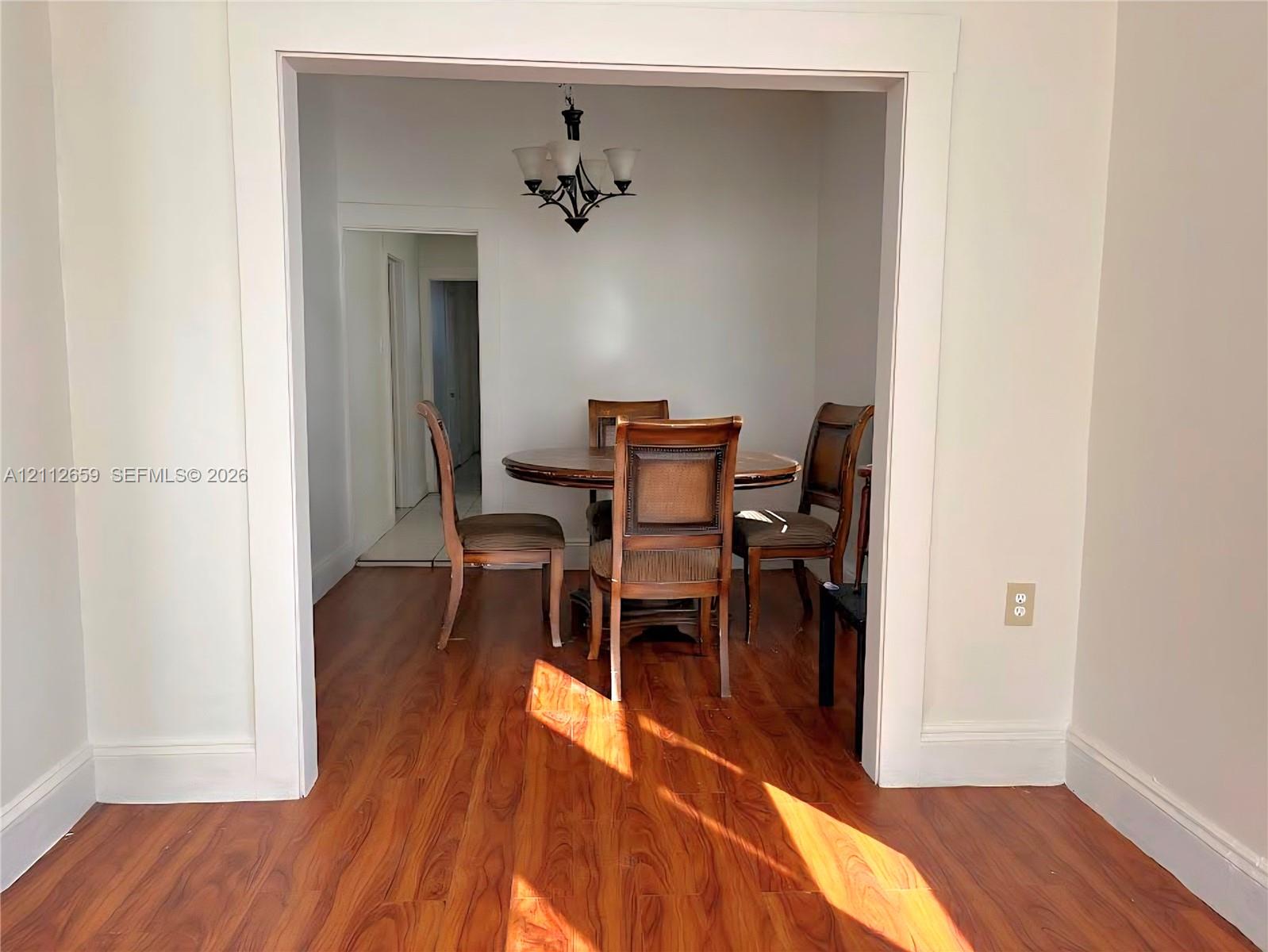 Wood-finish flooring, wide cased openings, and an overhead multi-arm chandelier Wood-finish flooring, wide cased openings, and an overhead multi-arm chandelier