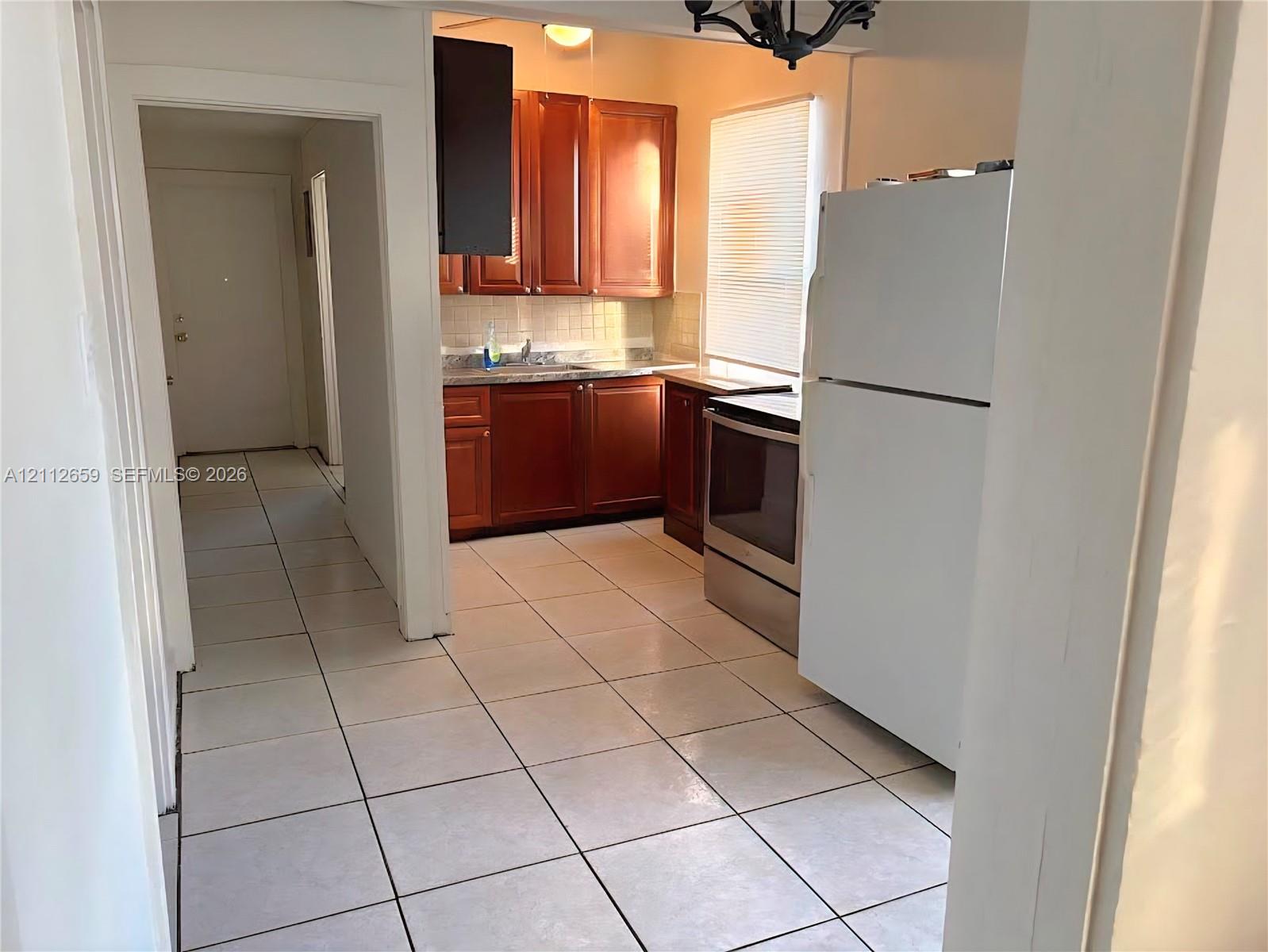 Kitchen featuring wood-finish cabinetry, tile flooring, and stainless steel appliances